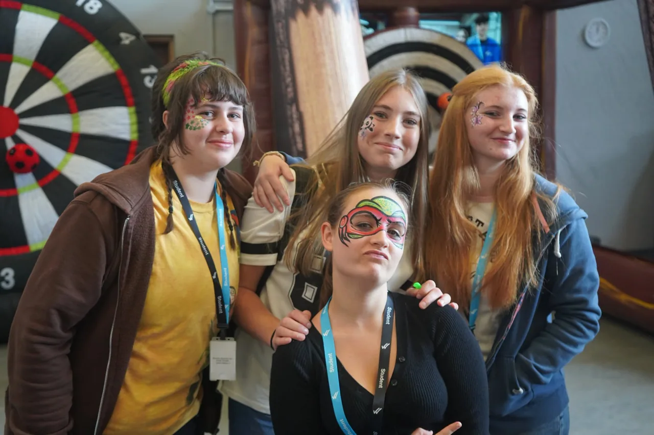 A group posing together at the Enrichment Fayres, including attendees with face painting