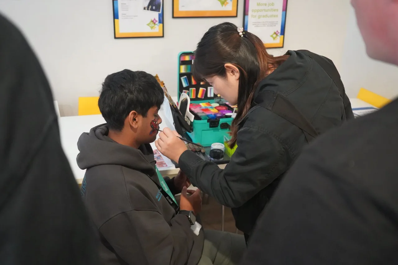 Mika applying face paint to an attendee at the college event