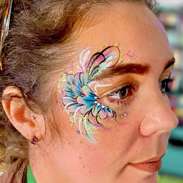 Blue and pink feather-style eye design with white swirls and gold accents