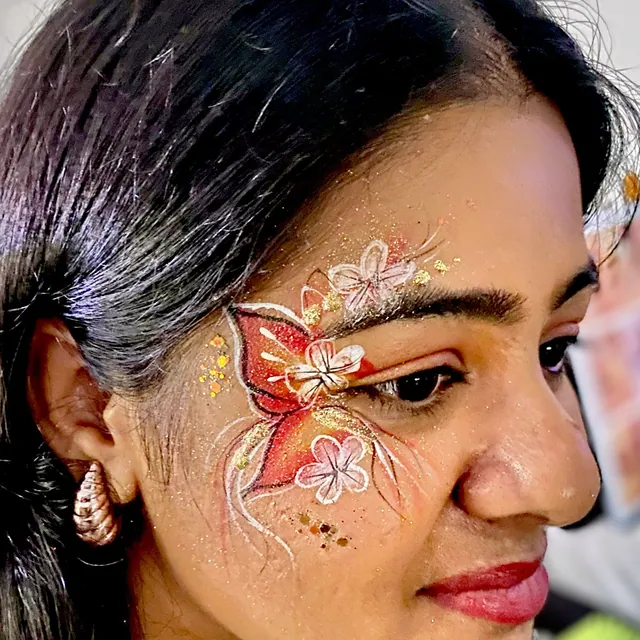 Red and orange butterfly eye design with white flowers and gold glitter