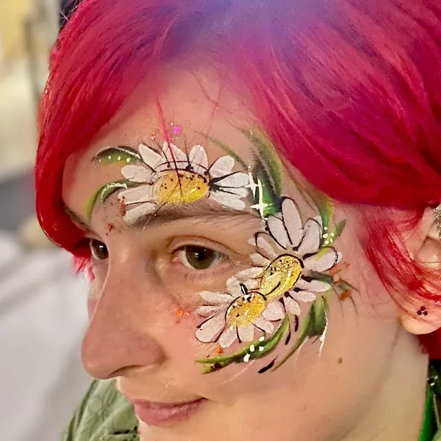 White daisy face painting with yellow centres and green leaves