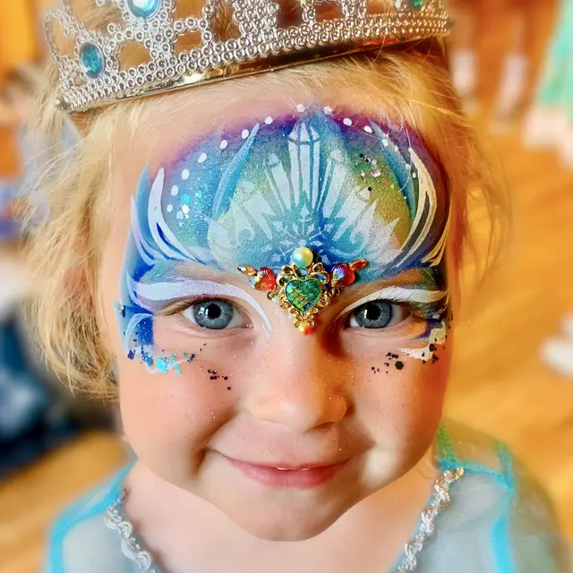 Blue princess face painting with a central gem cluster