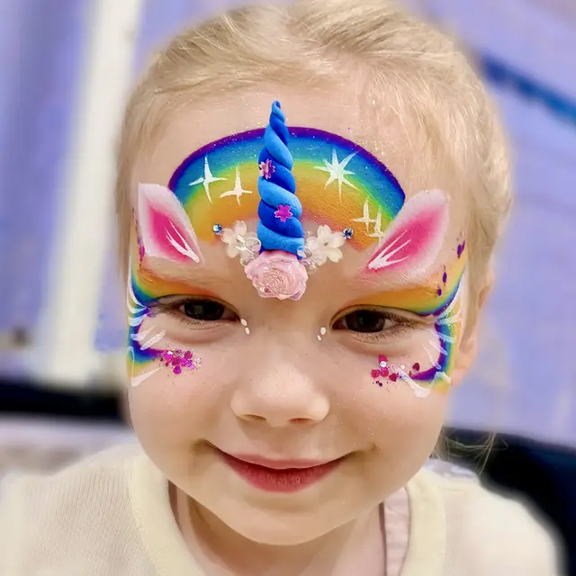 Rainbow unicorn face painting with pearl accents
