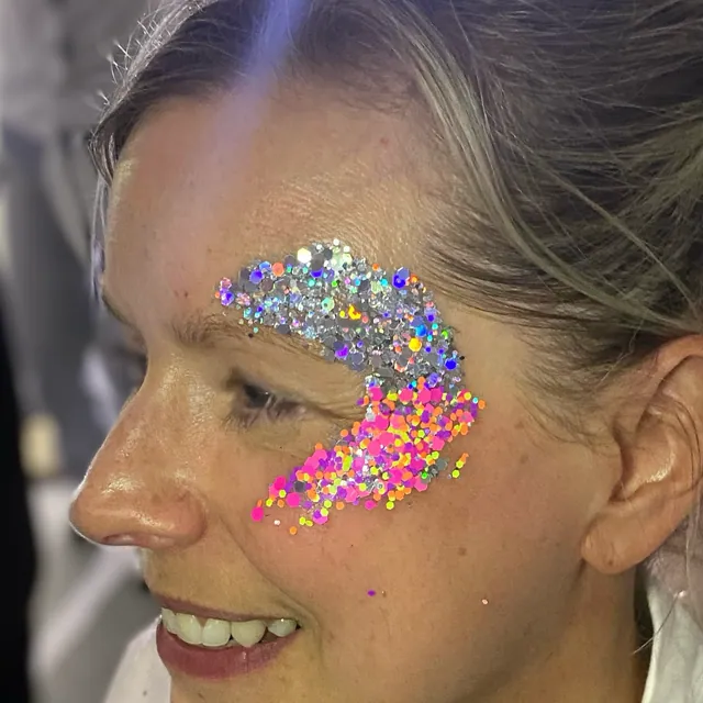 Silver holographic and neon pink glitter sweeping around the eye