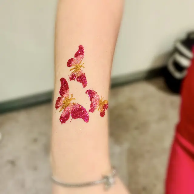 Pink glitter paw-print tattoos on an arm